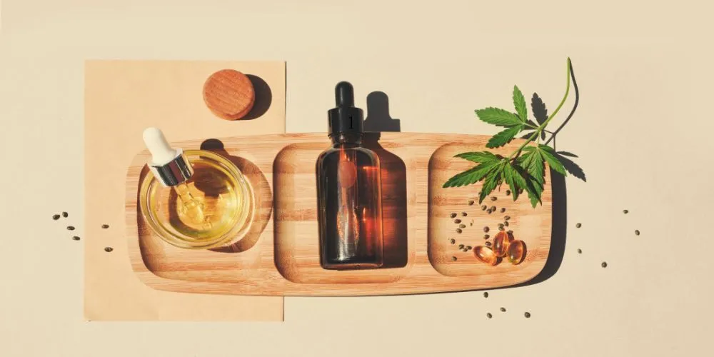 Extractos de CBD, cápsulas y hoja de cáñamo sobre bandeja de madera